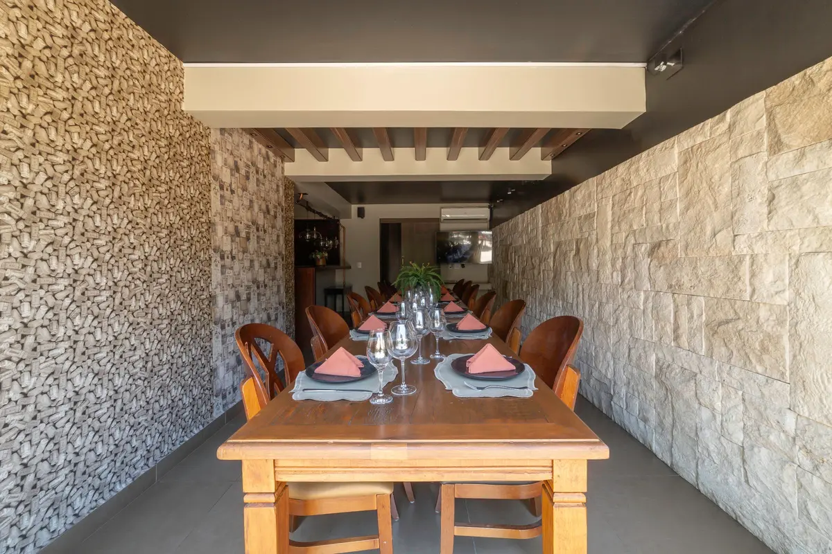 Enoteca do Vivá com mesa comprida de madeira e paredes de pedra