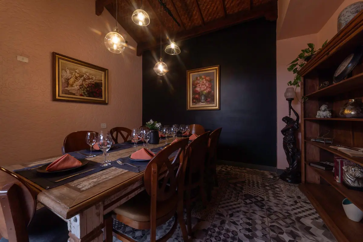 Sala privativa do Vivá com mesa posta para oito pessoas, estante de madeira e quadros
